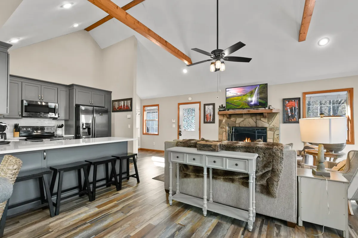An inviting kitchen and living area, featuring a kitchen island, a wood-burning fireplace, comfortable seating, and a TV. The space is designed for cooking, entertaining, and relaxing, with ample room for everyone to gather.