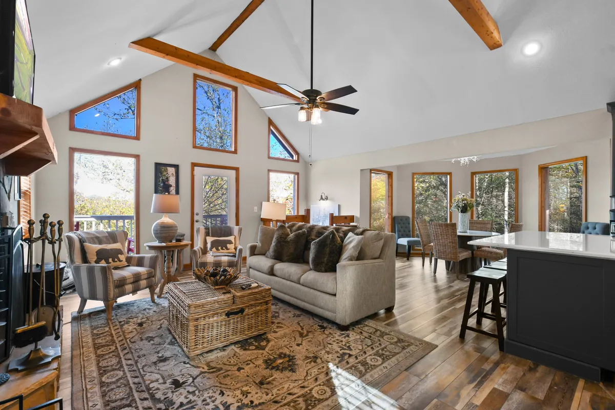 A cozy living room with a sofa and pillows facing large windows that allow for scenic views of the outdoors. The wooden beams and coffee table add rustic charm, and the space feels bright and tranquil—perfect for relaxing, reading, or enjoying the view after a day of exploring.