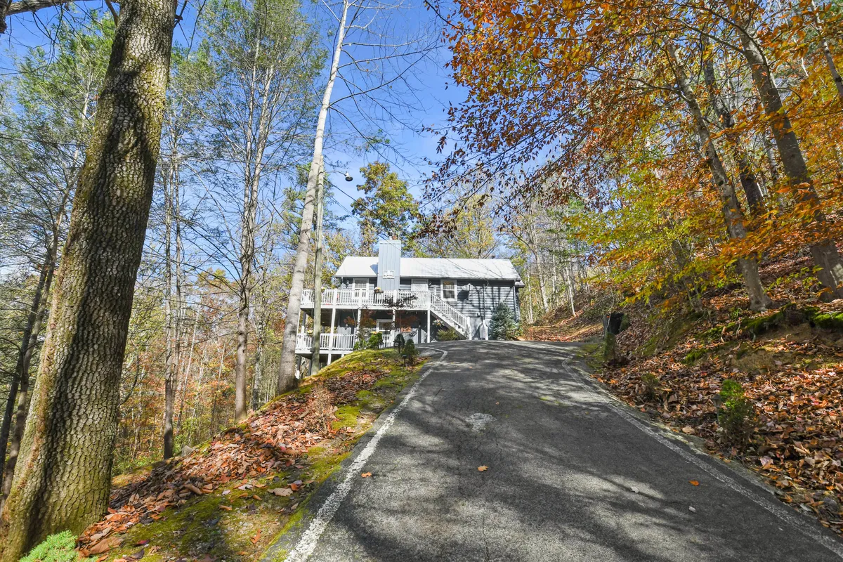 A wide exterior view of the house nestled among trees, with the driveway leading up and a porch ready for relaxation. The natural setting highlights the property’s proximity to the outdoors and its role as a comfortable home base for Smoky Mountain adventures.