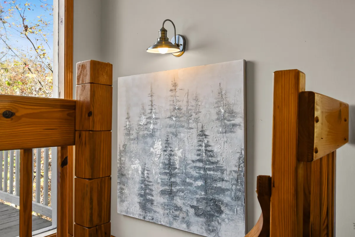An inviting nook featuring artwork of trees, wooden furniture, and soft natural light streaming through the window. The calm, understated decor emphasizes warmth and the connection to nature even while indoors.