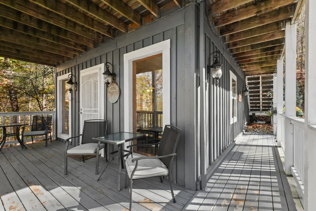 An inviting porch with a glass table, comfortable seating, wooden beams, and decorative lanterns offers a welcoming spot for guests to relax, enjoy the view, or host a casual gathering. The ambiance is tranquil, perfect for stargazing or sipping morning coffee.